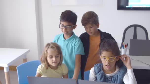 Školní chlapci a dívky sedí a stojí za stolem — Stock video