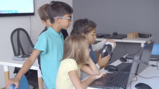 Groep van serieuze schoolkinderen zittend en staand aan het bureau — Stockvideo