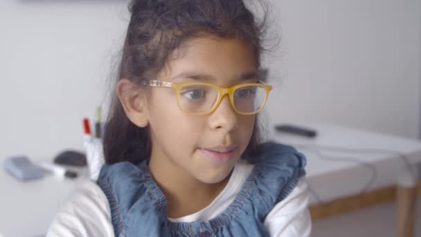 Alegre inteligente latina colegiala en gafas sentado en escritorio — Vídeos de Stock