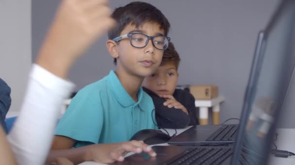 Concentrato scolaro in occhiali aiutare i compagni di classe a fare il compito — Video Stock