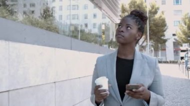 Odaklanmış genç iş kadını dışarıda yürüyor.