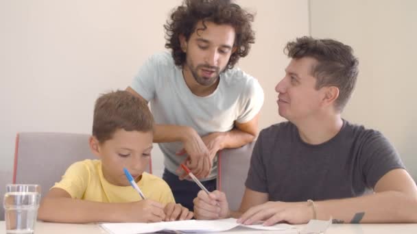 Dois pais ajudando o filho com a tarefa de escrita — Vídeo de Stock