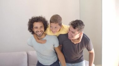 Neşeli çocuk ve iki babası evde eğleniyorlar.