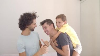 Neşeli çocuk ve iki babası evde eğleniyorlar.