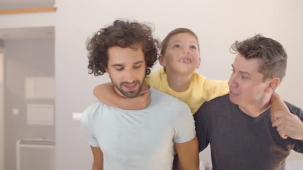 Happy kid i jego dwóch ojców korzystających z aktywności w domu — Wideo stockowe