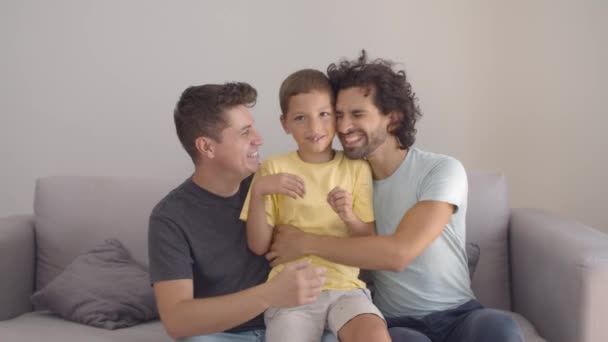 Pozitivní roztomilý chlapec objímající své dva šťastné tatínky — Stock video