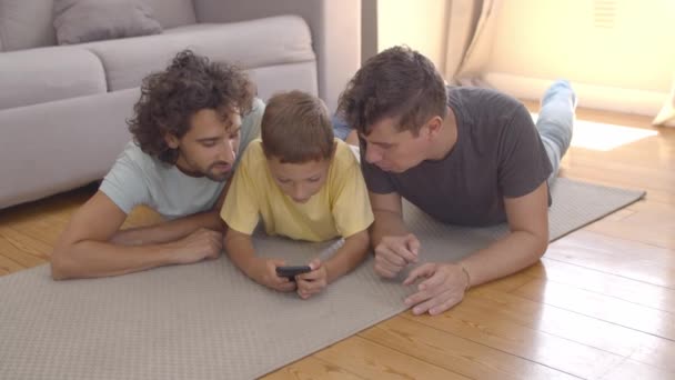 Anak fokus berbaring di lantai dekat ayah dan menggunakan aplikasi — Stok Video