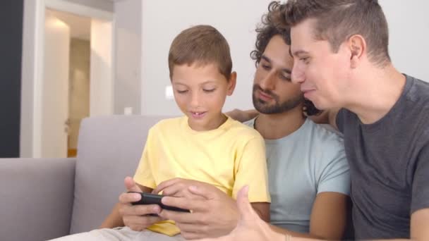 Pensive jongen zitten op vaders schoot en het bestuderen van nieuwe app — Stockvideo
