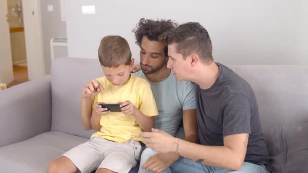 Skupiony chłopiec siedzi na kolanach ojców i gra online — Wideo stockowe