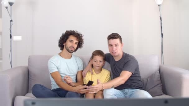 Zwei fokussierte Väter und ihr Sohn geben Parameter im neuen Fernseher vor — Stockvideo