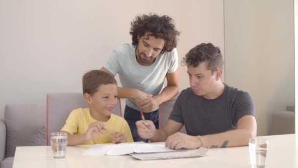 Dva otcové pomáhají synovi se školním domácím úkolem — Stock video
