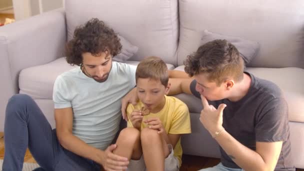 Nyugodt meleg szülők és gyerekek sütit esznek és filmet néznek — Stock videók