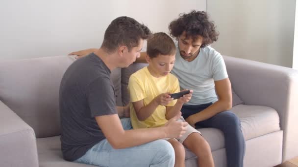 Dva otcové pomáhají synovi s online aplikací na mobilním telefonu — Stock video