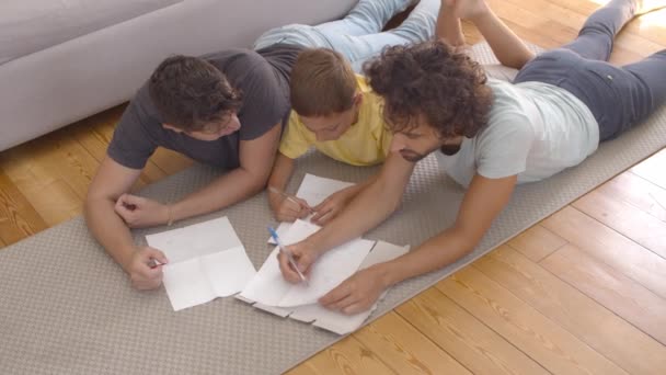 Ontspannen vaders en kind liggend op de vloer en tekening — Stockvideo