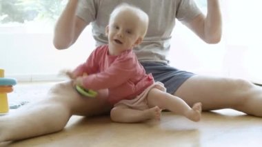 Tanımlanamayan baba, dışarı çıkmış bebekle oynuyor ve oturuyor.