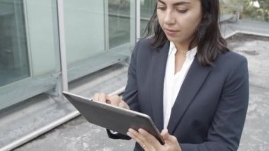 Takım elbiseli düşünceli Latin iş kadını tablet kullanıyor