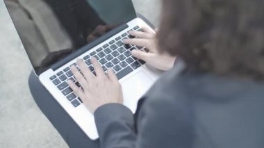 Laptop ve iş kadınının elleri dışarıda oturuyor.