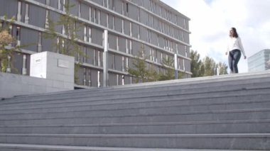 Gülümseyen genç iş kadını aşağıya iniyor.