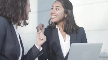 Neşeli ofis arkadaşları dışarıda oturup dizüstü bilgisayar kullanıyorlar.