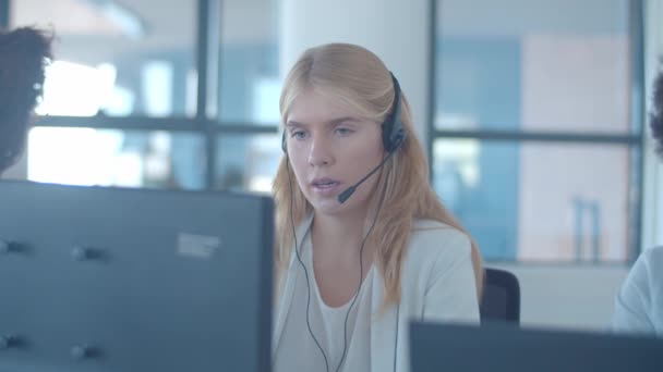 Operadora femenina joven seria en auriculares hablando con el cliente — Vídeos de Stock