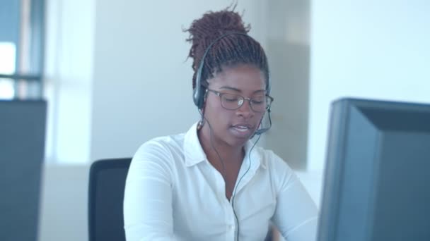Skupiony afro-amerykański operator w słuchawkach rozmawiający z klientem — Wideo stockowe