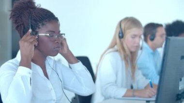 Odaklanmış Afro-Amerikan çağrı merkezi operatörü kulaklık takıyor.