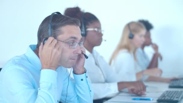 Serious male call center consultant putting on headset — Video Stock