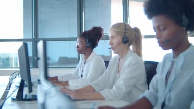 Bilgisayarlarda çalışan farklı kulaklıklarda odaklanmış operatörler