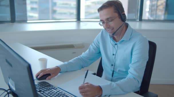 Positieve mannelijke operator in headset neemt oproep aan — Stockvideo