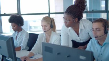 Genç Afrikalı Amerikalı yönetici çağrı merkezi çalışanlarına yardım ediyor