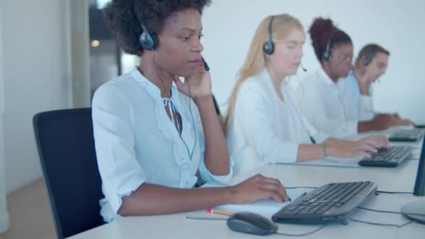 Equipo de operadores de call center en auriculares sentados en fila — Vídeo de stock