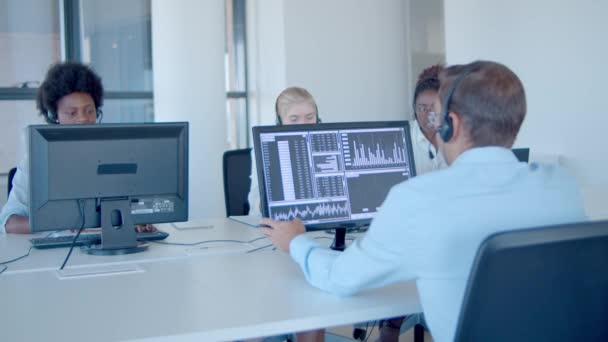 Equipo de corredores financieros en auriculares que trabajan en la oficina — Vídeo de stock