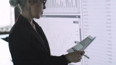 Başarılı iş kadını notlar alıyor ve ekranın yanında duruyor.