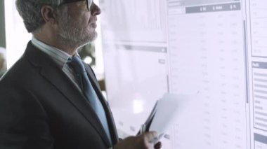 Profesyonel kıdemli işadamı büyük ekranın önünde duruyor.