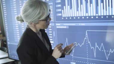 Kendine güvenen kadın CEO tablet üzerinde kayıyor ve daktilo yazıyor