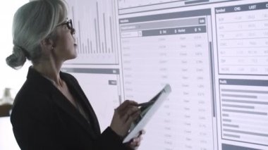 Büyük ekranın önünde duran profesyonel iş kadını.