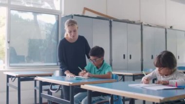 Dost canlısı öğretmen, öğrenci çocuğa yardım ediyor.