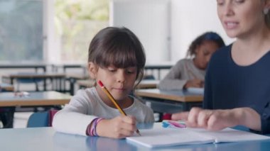 Bayan öğretmen sınıfta öğrenci kıza doğru yürüyor.