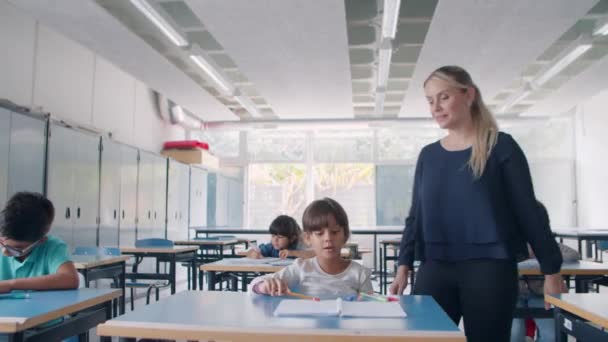 Junge Lehrerin läuft zwischen Schreibtischen — Stockvideo