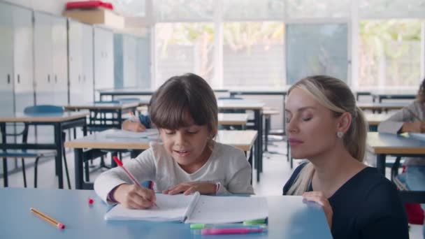 Vriendelijke vrouwelijke schooljuf helpen Latijn schoolmeisje — Stockvideo