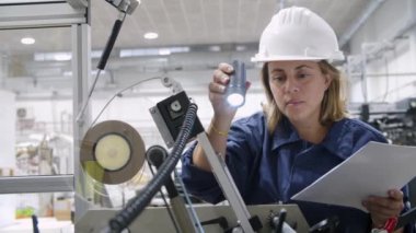 Ciddi kadın fabrika işçisi ekipman özelliklerini kontrol ediyor