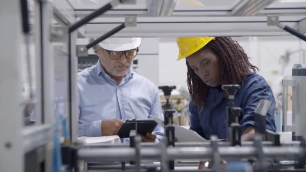 Älterer Fabrikingenieur bildet schwarzen Mitarbeiter aus — Stockvideo