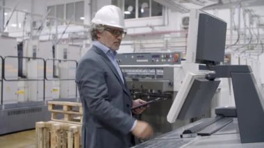 Odaklanmış eski fabrika mühendisi endüstriyel makineyi kontrol ediyor