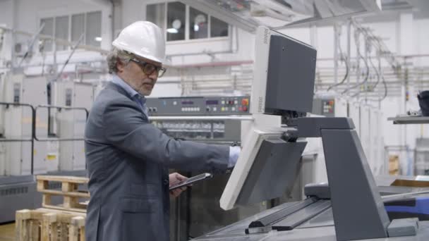 Velho engenheiro de fábrica masculino verificando máquina industrial — Vídeo de Stock