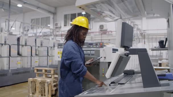 Gerichte zwarte fabrieksmedewerker die industriële machine werkt — Stockvideo