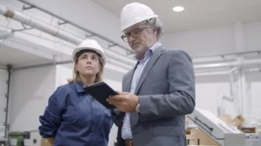Tablet kullanan ve makine çalışma sürecini gösteren eski mühendis