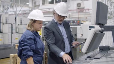 Eski mühendis fabrika çalışanı yeni makineyi çalıştırıyor.