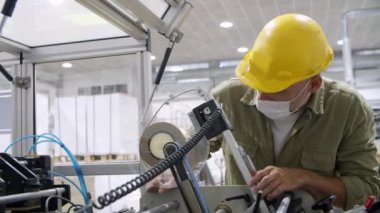 Koruyucu kasklı düşünceli adam mekanizmaya bakıyor.