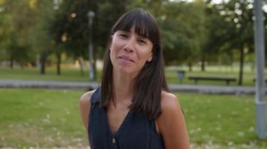 Şehir parkında dikilen mutlu siyah saçlı kadın