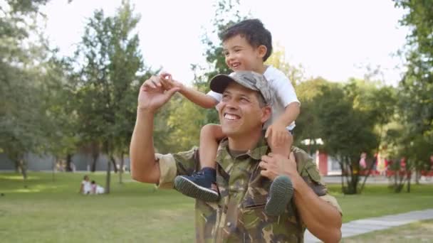 Parkta babasının omuzlarına binen mutlu küçük çocuk. — Stok video